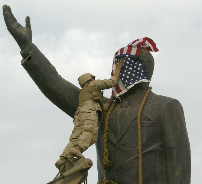 A US Marine covers a statue of Iraqi President Saddam Hussein with the US flag in Baghdad’s al-Fardous square in April 2003, before the statue was toppled. EPA PHOTO AFPI/RAMZI HAIDAR