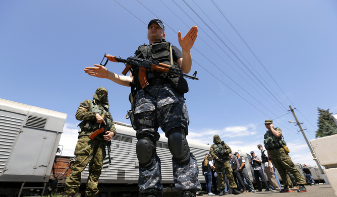 A train carrying the remains of crash victims is guarded by pro-Russian separatists. EPA/Robert Ghement